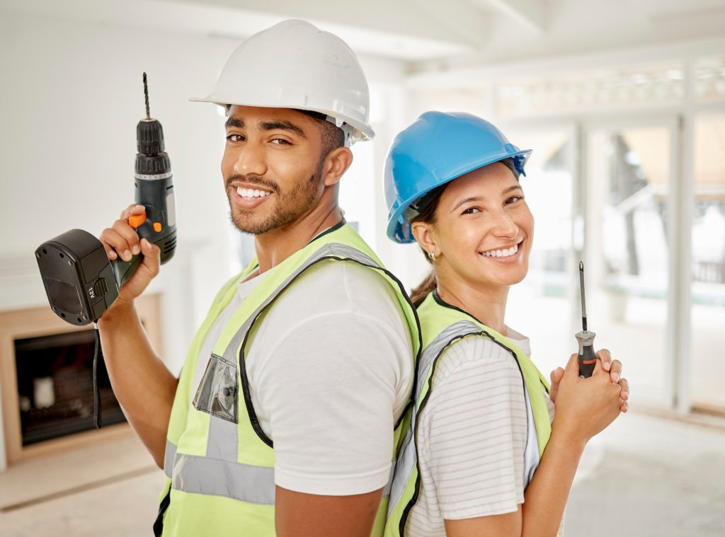 Shot of two construction workers standing back to back in a house and holding maintenance equipment